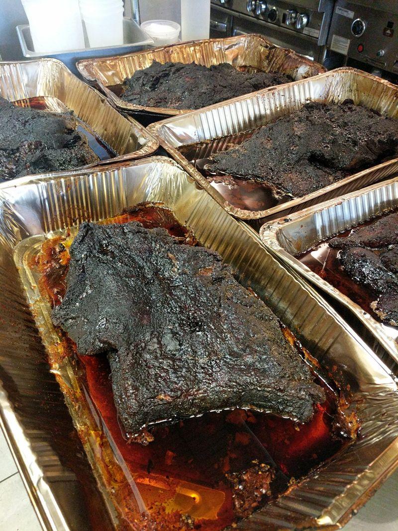 Smoked briskets resting in foil pans